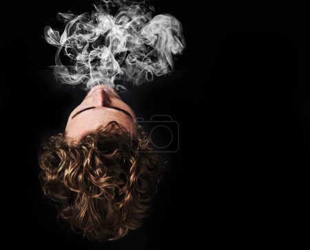Foto de Hombre fumando marihuana, drogas o cigarrillo en estudio aislado en maqueta de fondo negro. Humo, vapor y persona exhalan cannabis, hierba y adicción al tabaco, 420 cbd o abuso de sustancias en vista superior. - Imagen libre de derechos