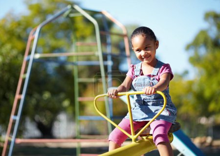 Photo for Girl child, smile and seesaw at park, school or outdoor in spring for playful games, adventure or freedom. Kid, playground and happy in kindergarten, nature and summer sunshine with thinking by trees. - Royalty Free Image