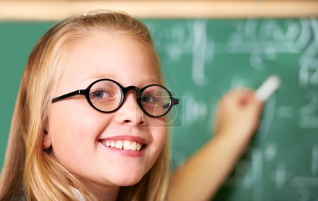 Photo for Portrait, nerd and happy kid writing on chalkboard in class for learning, education and study math. Face, glasses and smile of geek at school, cute girl child and student in classroom in Australia. - Royalty Free Image