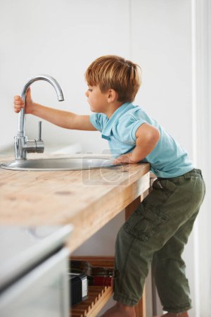 Photo for Kids, fantasy and a boy in the kitchen sink, playing a game in his home as a plumber character. Children, basin and counter with a young male kid in a modern apartment for imaginary plumbing. - Royalty Free Image