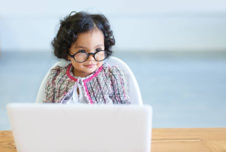 Photo for Young child, laptop and glasses at table for online learning education, development or growth. Female toddler person, internet or connection homework studying, virtual school or youth comedy dress up. - Royalty Free Image
