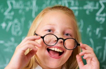 Photo for Excited, smile and portrait of child student in classroom with glasses by board for lesson or studying. Education, learning and happy young girl kid with positive attitude for scholarship in school - Royalty Free Image