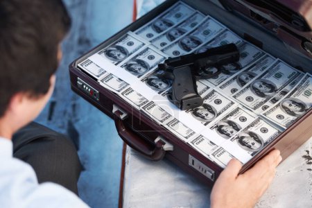 Photo for Businessman, gun and briefcase with money for crime, corruption, thief and fraud outdoor for financial crisis. Professional, man and weapon with cash, finance and secret for laundering, scam or loan. - Royalty Free Image