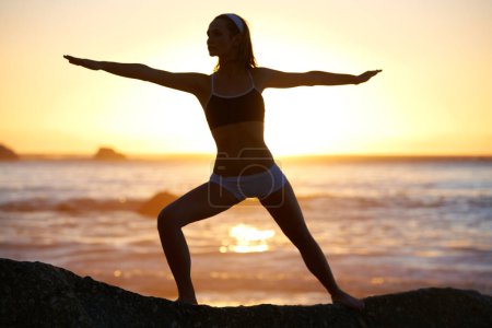 Photo for Woman, sunset and fitness on beach with warrior pose for stretching of muscles at sunrise. Person, shadow and balance for zen, healthy and mindset with movement with relaxing with outdoor yoga. - Royalty Free Image