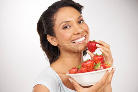 Photo for Happy, strawberries and portrait of woman in a studio for wellness, nutrition and organic diet. Smile, vitamins and young female person eating a fruit for healthy vegan snack by gray background - Royalty Free Image