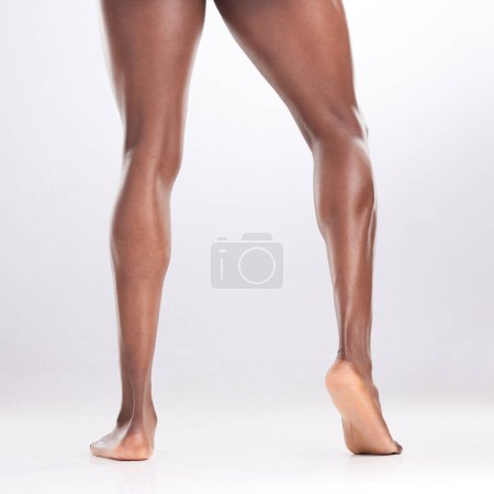 Téléchargez les photos : Il ne saute JAMAIS le jour des jambes. un homme méconnaissable montrant ses jambes musclées tout en posant sur un fond blanc - en image libre de droit