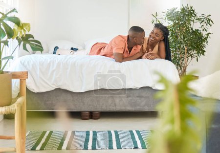 Photo for Affectionate young african american couple holding hands while relaxing together on a bed at home. Happy black boyfriend and girlfriend sharing intimate moments in a loving relationship while bonding. - Royalty Free Image