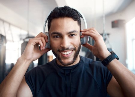 Foto de Ahora estoy bombeado. Retrato de un joven deportivo escuchando música mientras hace ejercicio en un gimnasio - Imagen libre de derechos