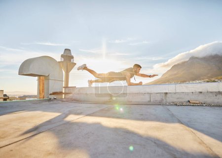 Photo for It time for you discover just how capable you are. a man doing a single-arm plank while on a rooftop - Royalty Free Image