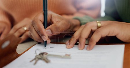 Photo for Closeup, hands and signature on mortgage paperwork for finance, home contract or a loan. Investment, legal and a couple writing on a document for keys of a house, ownership and agreement for a deal. - Royalty Free Image