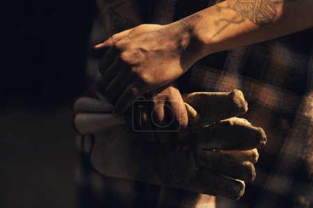 Foto de Las manos trabajadoras tienen mucho orgullo. un irreconocible sosteniendo un par de guantes mientras trabaja en una fundición - Imagen libre de derechos