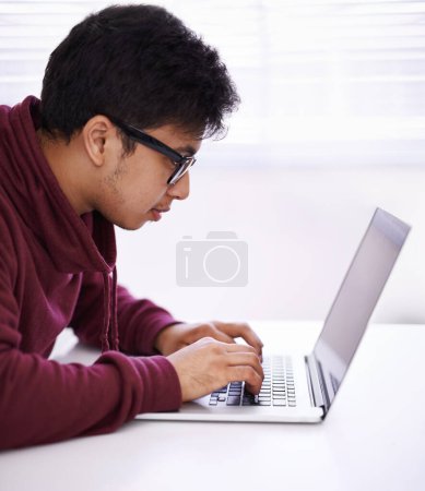 Foto de Hacer la tarea de manera eficiente. un joven guapo trabajando en su portátil en una oficina - Imagen libre de derechos
