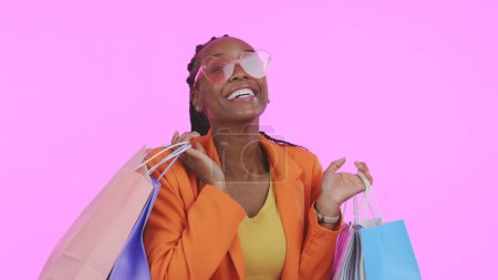 Photo for Woman, shopping bag and sunglasses for fashion sale, discount and giveaway prize or competition in studio. Portrait of african person or excited customer with gift or funky style on pink background. - Royalty Free Image