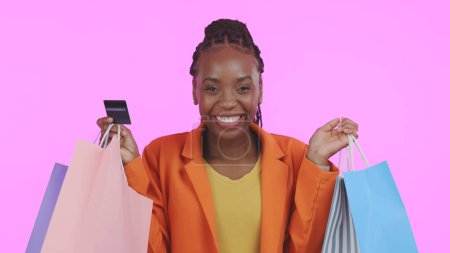 Photo for Woman, portrait and credit card with shopping bag for financial success, sale and discount on pink background. Excited customer or african winner in celebration for banking, fashion or gift in studio. - Royalty Free Image