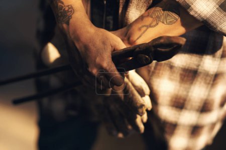 Téléchargez les photos : Les mains de forgeron sont ses meilleurs outils. une personne méconnaissable tenant une paire de gants pendant qu'elle travaillait dans une fonderie - en image libre de droit