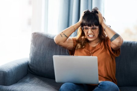 Téléchargez les photos : Qu'est-ce qui ne va pas ? une femme à l'air frustrée en utilisant son ordinateur portable à la maison - en image libre de droit