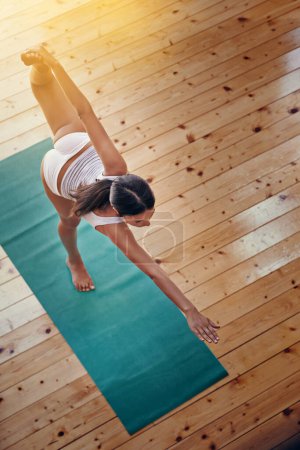 Téléchargez les photos : Yoga donne à son corps une séance d'entraînement complète. Plan grand angle d'une jeune femme faisant du yoga à l'intérieur - en image libre de droit