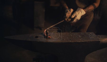 Foto de Incluso el acero más fuerte a veces puede doblarse. un herrero que trabaja con una varilla de metal caliente en una fundición - Imagen libre de derechos