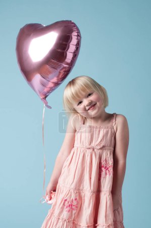 Photo for Everyone deserves balloons. an adorable little girl holding a heart balloon against a studio background - Royalty Free Image