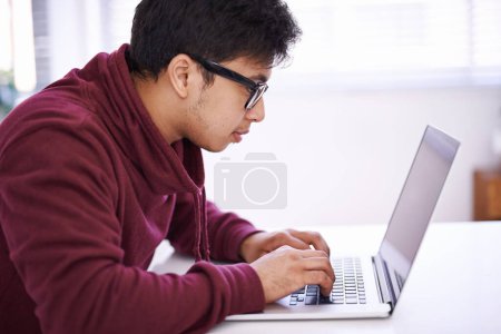 Téléchargez les photos : Pas de distractions parce que je travaille dur. un beau jeune homme travaillant sur son ordinateur portable dans un bureau - en image libre de droit