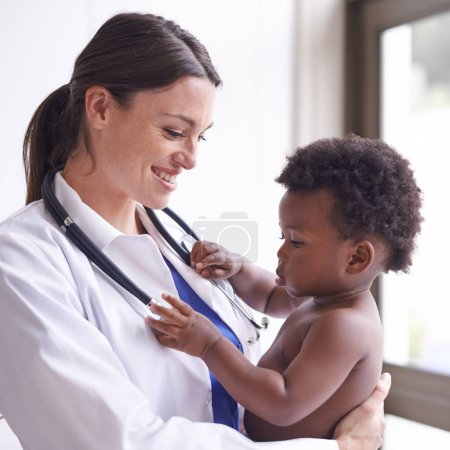 Téléchargez les photos : Juste pour un examen pédiatrique de routine. une pédiatre féminine qui fait un check-up sur un adorable petit garçon - en image libre de droit