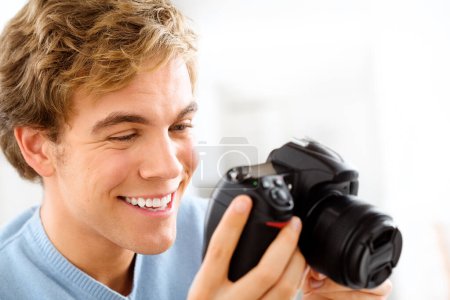Photo for Looking for that perfect shot. a young man using his digital camera at home - Royalty Free Image