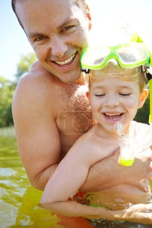 Téléchargez les photos : Profiter de notre journée au bord du lac. Heureux père et fils nageant dans un lac - en image libre de droit