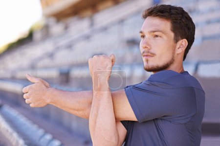 Photo for Take the care to prepare. a handsome young man stretching at an athletics arena - Royalty Free Image