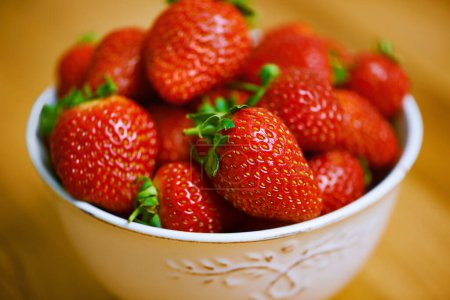 Photo for Fresh from the garden. a bowl of strawberries on a wooden table - Royalty Free Image