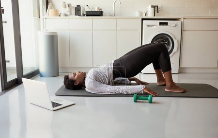 Téléchargez les photos : Inclure l'exercice dans votre routine d'autosoin. une jeune femme utilisant un ordinateur portable pendant l'exercice à la maison - en image libre de droit