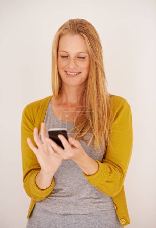 Téléchargez les photos : Télécharger une nouvelle application est si facile. une femme heureuse envoyant un SMS sur son téléphone portable - en image libre de droit