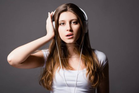 Photo for Music is art that speaks to the heart. a young woman listening to music against a studio background - Royalty Free Image