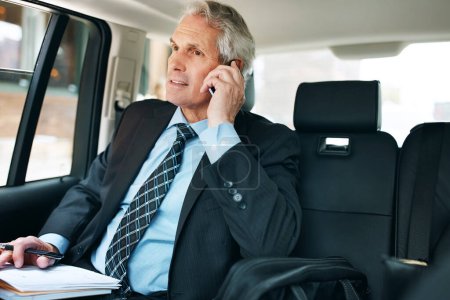 Photo for He moves to where the business is. a mature businessman using a mobile phone in the back seat of a car - Royalty Free Image