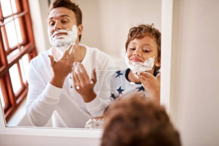Photo for Heres how dad manages to look ten years younger. a man teaching his young son how to shave at home - Royalty Free Image