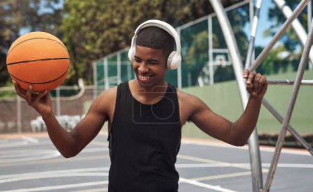 Téléchargez les photos : Regarde-moi claquer du dunk. un jeune homme sportif écoutant de la musique tout en jouant au basket sur un terrain de sport - en image libre de droit