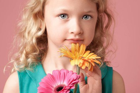Téléchargez les photos : Des fleurs pour la belle fille. une petite fille tenant des fleurs sur un fond de studio - en image libre de droit