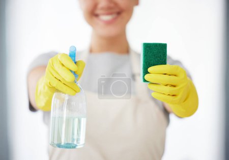 Foto de Una mujer irreconocible sosteniendo un producto de limpieza y una esponja mientras limpia su apartamento. Un limpiador doméstico desconocido que usa guantes de limpieza de látex. - Imagen libre de derechos