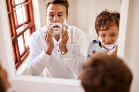 Foto de Enseñar a su hijo a afeitarse no es una tarea pequeña. un hombre enseñando a su hijo a afeitarse en casa - Imagen libre de derechos