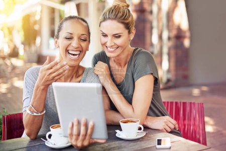 Photo for Thats so funny. two women sitting with a tablet at a coffee shop - Royalty Free Image
