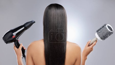 Photo for Volume or no volume. Rearview shot of a woman with sleek hair holding a hairdryer and blow-dry brush - Royalty Free Image