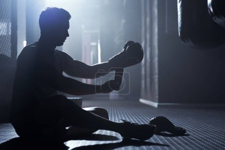 Photo for Gearing up for some powerful punches. a sporty young man strapping his gloves while boxing in a gym - Royalty Free Image