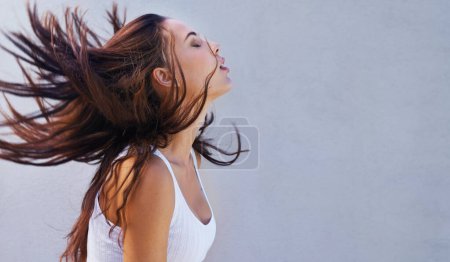 Téléchargez les photos : C'est bon de baisser les cheveux. une belle jeune femme jetant ses cheveux bruns - en image libre de droit
