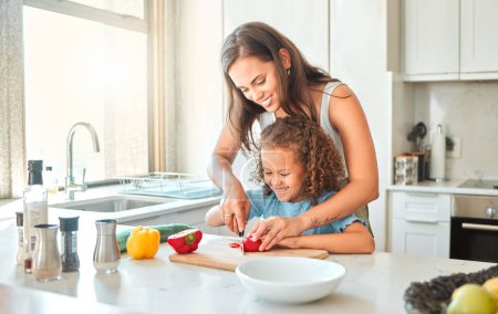 Photo for Loving mother and small daughter chopping vegetables and preparing vegetarian meal in the kitchen at home. Girl bonding with mother while learning to cook. - Royalty Free Image