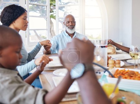 Téléchargez les photos : Tu sais toujours vers qui te tourner. une belle famille bénissant la nourriture avec une prière à la table ensemble à la maison - en image libre de droit
