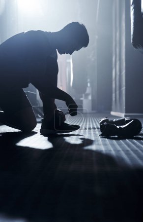 Photo for Work hard and trust the process. a sporty young man tying his laces before boxing in a gym - Royalty Free Image