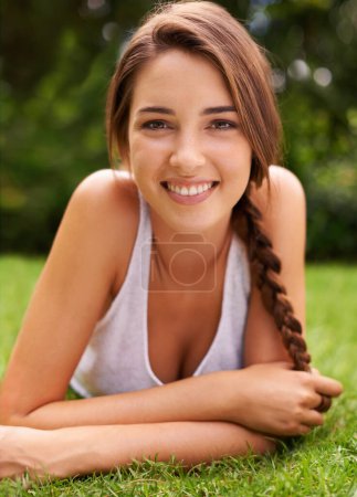 Téléchargez les photos : Elle adore être à l'extérieur. Portrait d'une jolie jeune femme allongée sur l'herbe - en image libre de droit