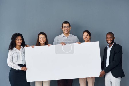 Foto de Muéstrales a todos tu mensaje. Retrato de un grupo de empresarios sosteniendo un cartel negro mientras están de pie sobre un fondo gris - Imagen libre de derechos