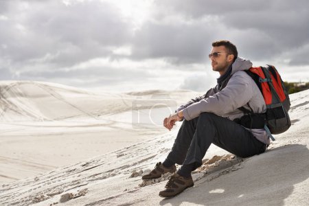 Photo for Appreciating the nature that surrounds him. a handsome male hiker sitting on the sand dunes - Royalty Free Image