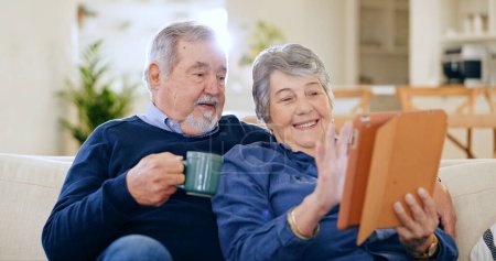 Photo for Tablet, coffee and a senior couple in their home to relax together during retirement for happy bonding. Technology, smile or love with an elderly man and woman drinking tea in their living room. - Royalty Free Image