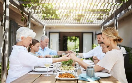 Téléchargez les photos : Dire grâce avant un repas est une tradition de longue date. une famille disant grâce tout en étant assis ensemble à la table à manger - en image libre de droit